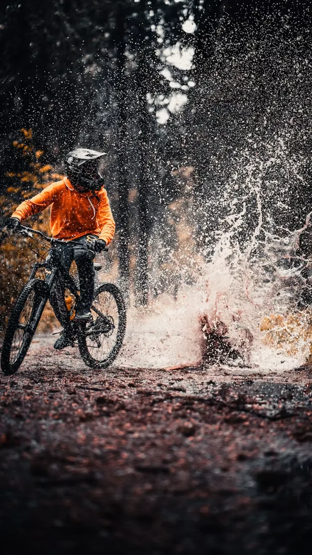 Mountain biker splashing through water on a forest trail